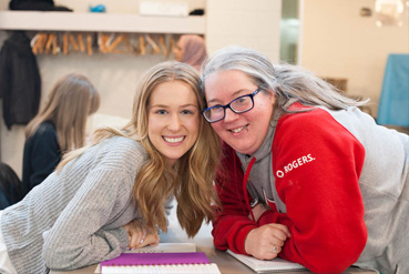 two women smiling and looking towards the camera