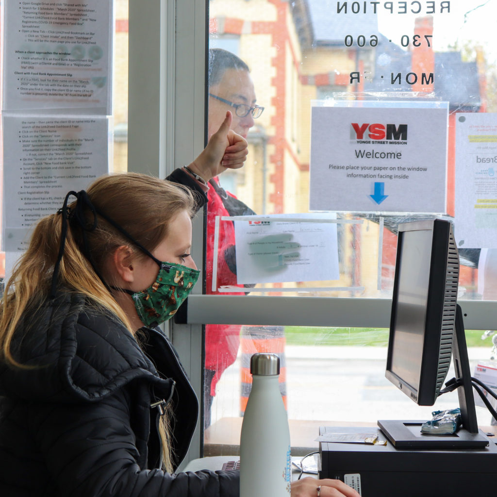 YSM staff give thumbs up to community member at the Food Bank