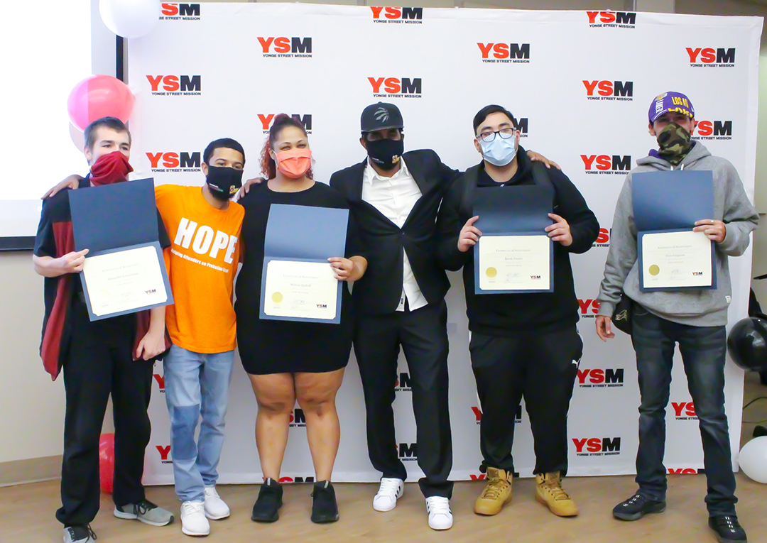 Two YSM Staff stafnd with 4 graduates from YSM's HOPE program stand together holding their certificates and smiling through PPE masks.