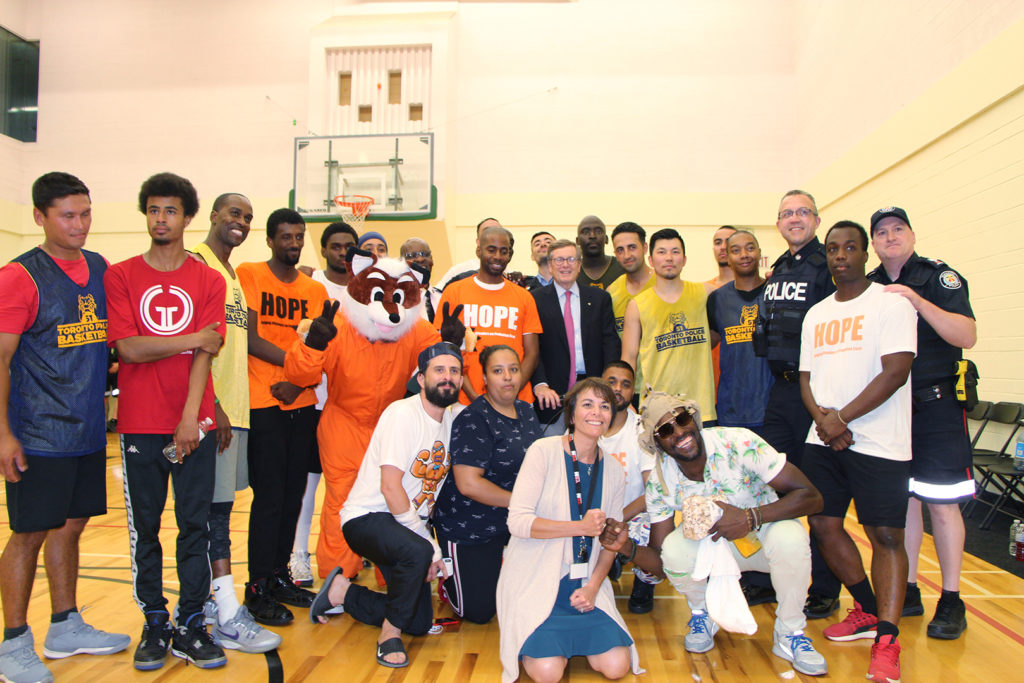 Group photo of HOPE participants and police officers at a friendly basketball game
