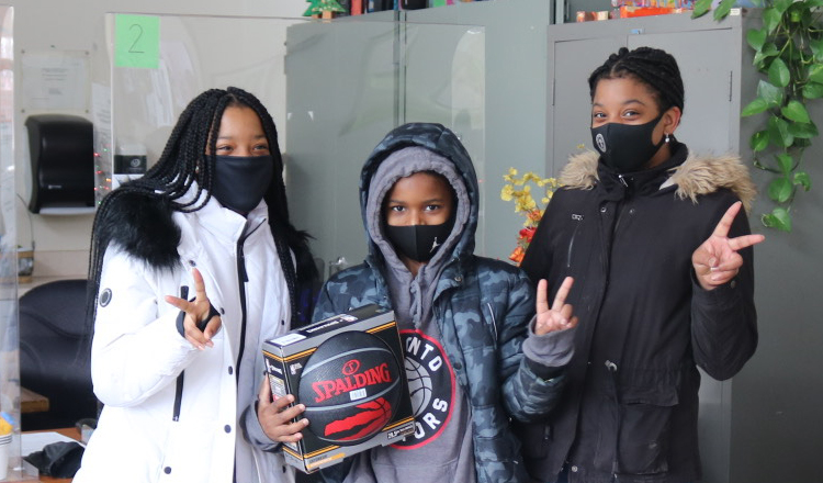 three youth wearing masks holding a Raptor's basketball
