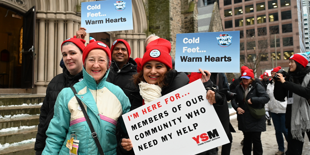 Group holds signs outside a church YSM Winter Walk